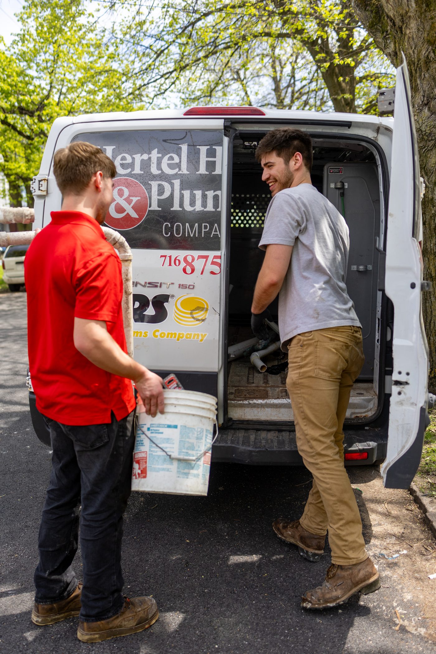 Two Hertel plumbers loading pipe into a service van