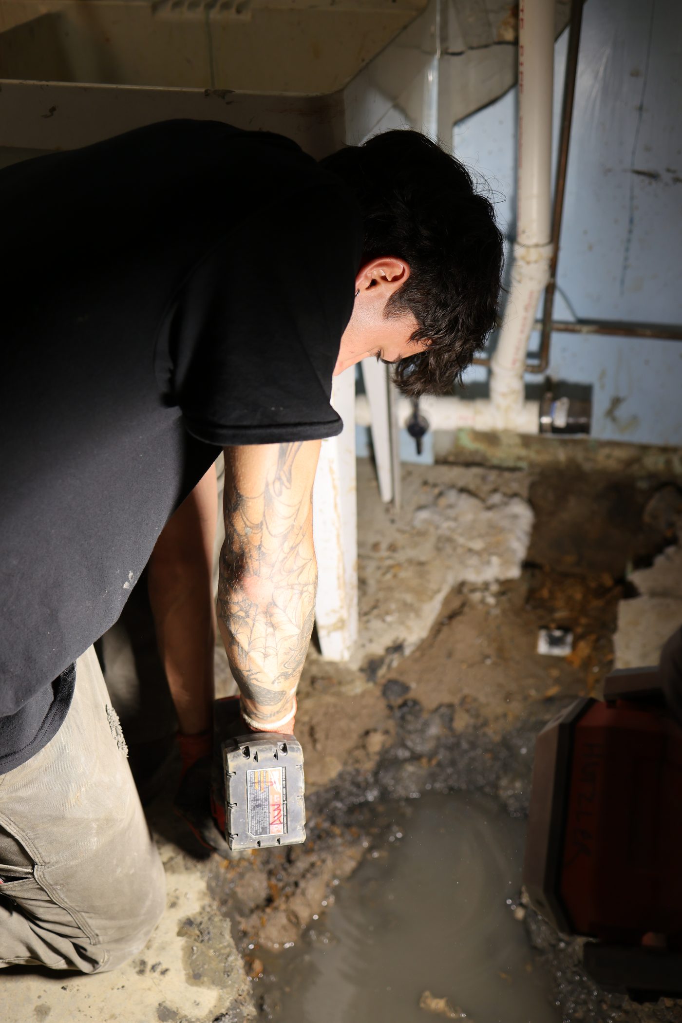 A Hertel plumber breaking through a basement slab to reach a buried line